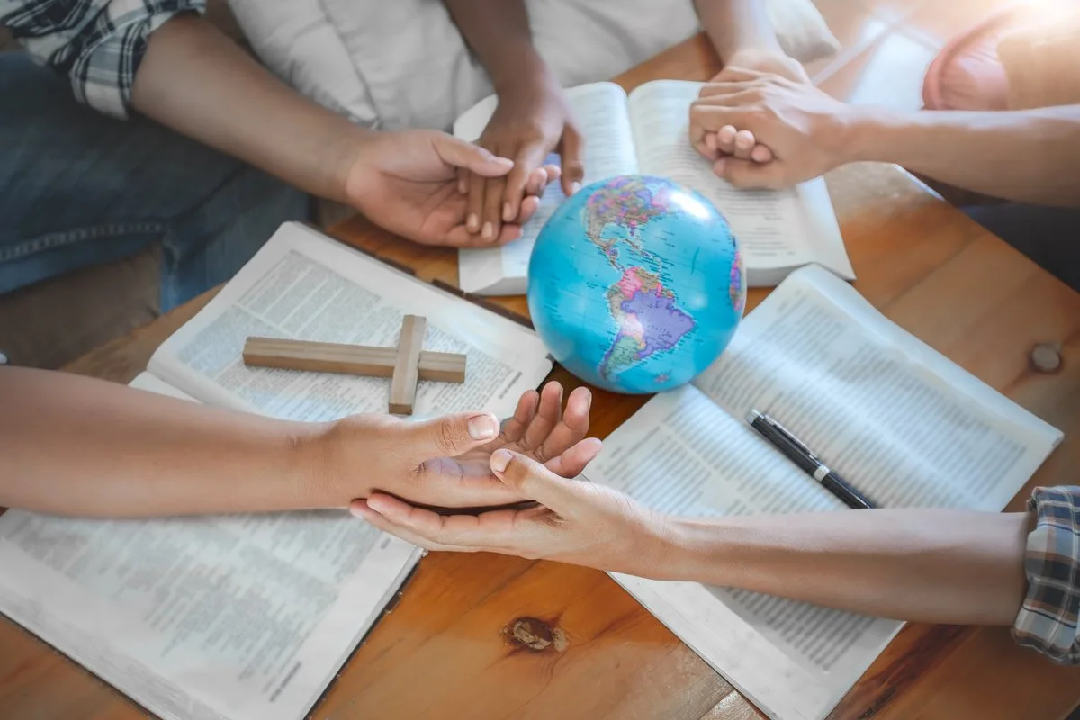 People gathered around a Bible and a globe, from ARM’s original website